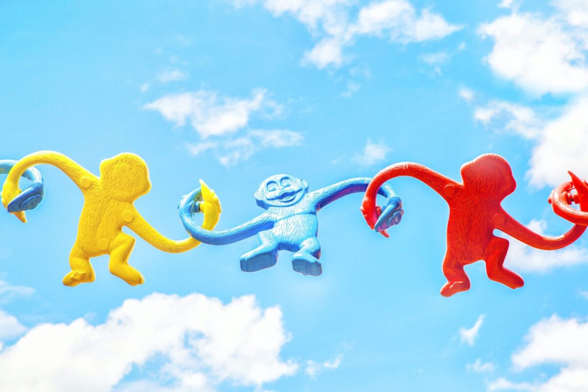 chain of plastic monkeys against cloudy blue sky